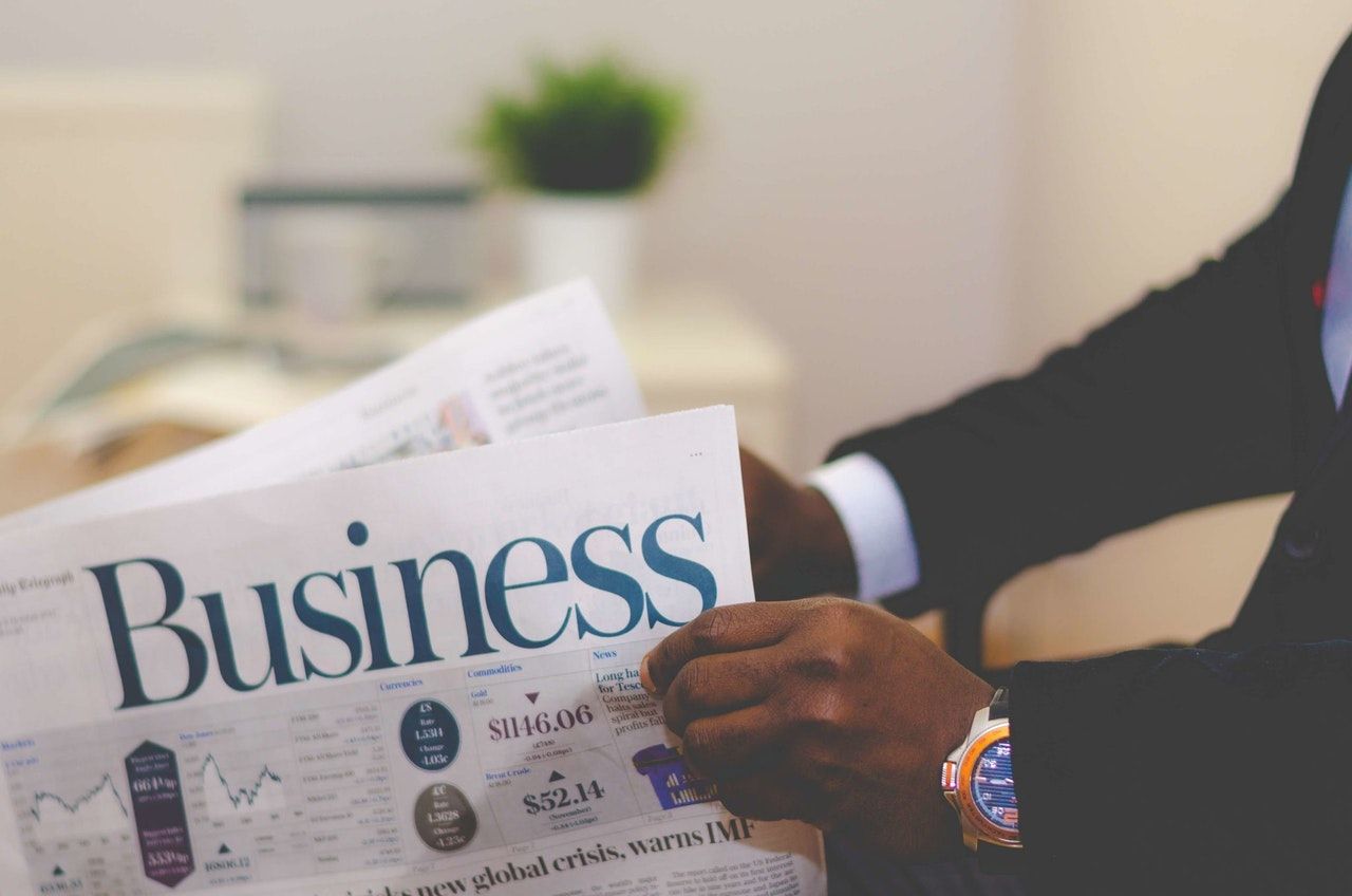 person holding the Business section of a newspaper