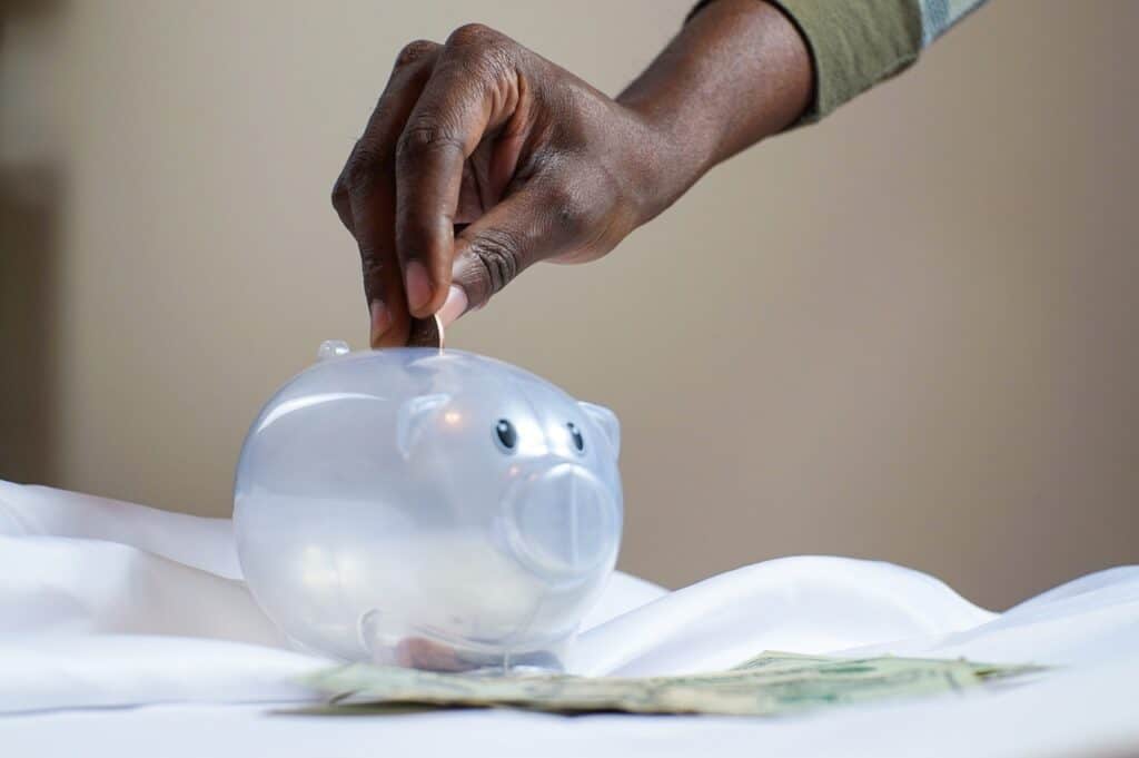 putting money in a plastic piggy bank