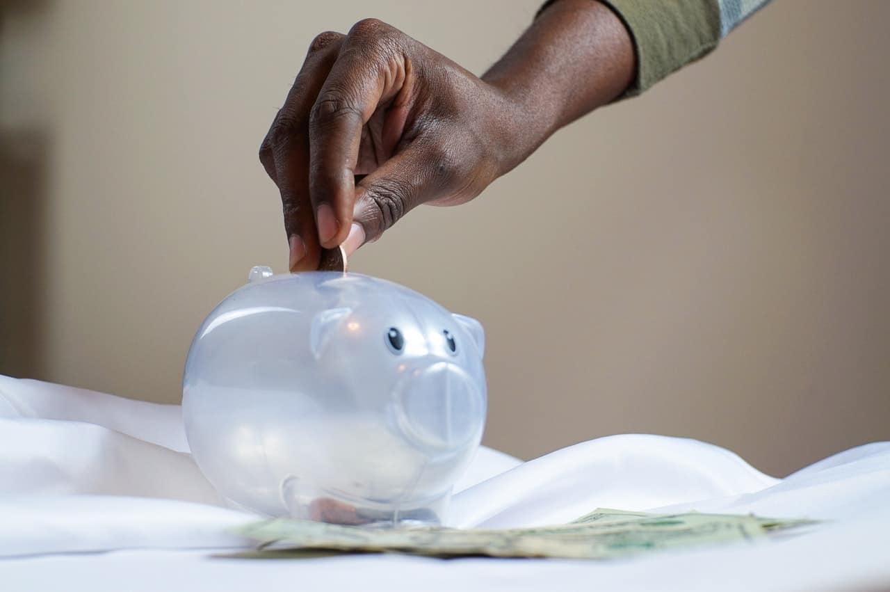 putting money in a plastic piggy bank